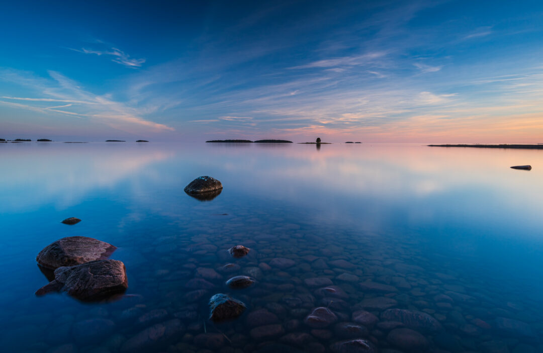 Stillness of Lake Vanern reflects a stunning sunset in Sweden’s tranquil landscape